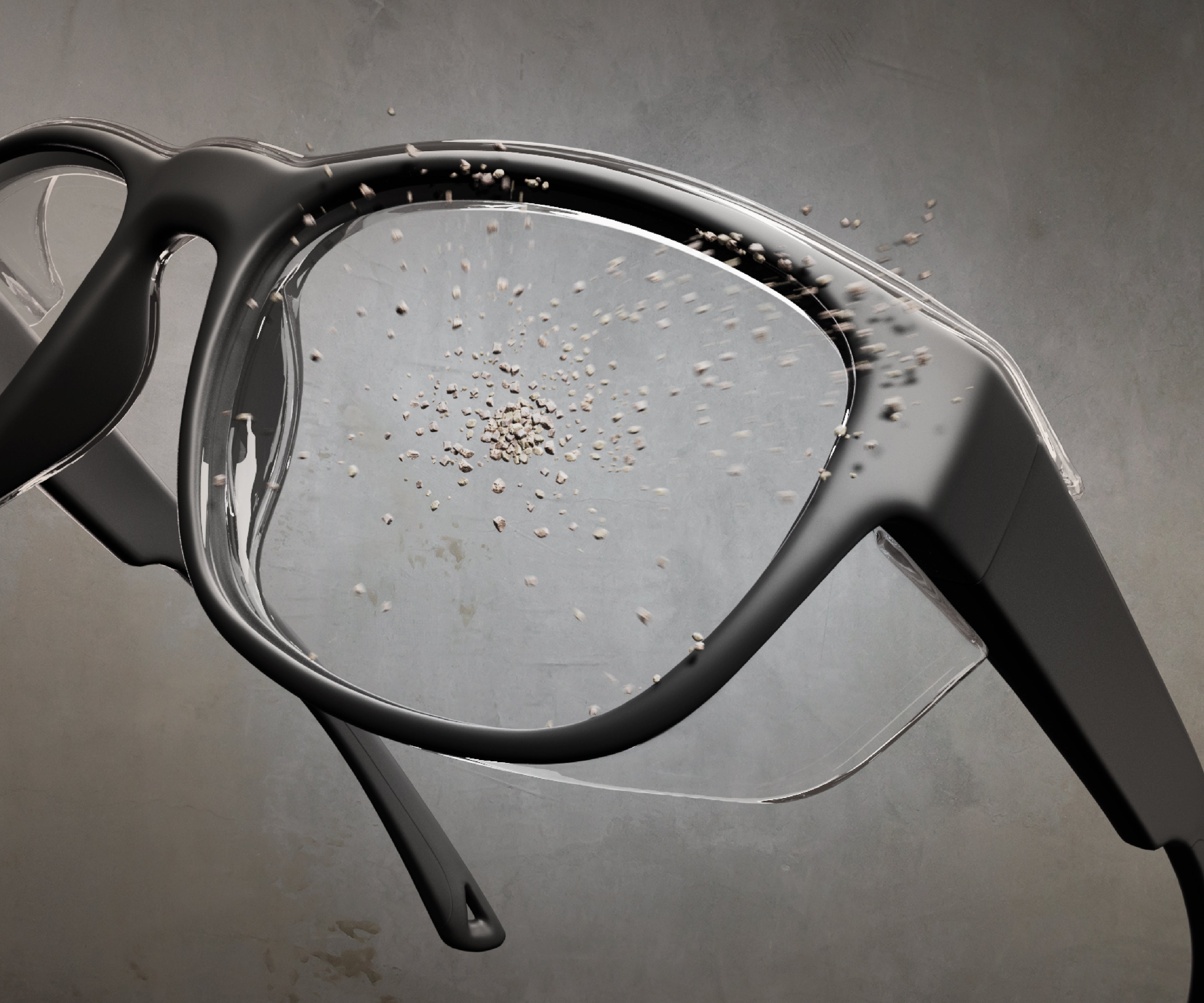Close-up of a pair of prescription safety glasses with small stones hitting the lenses against a gray background